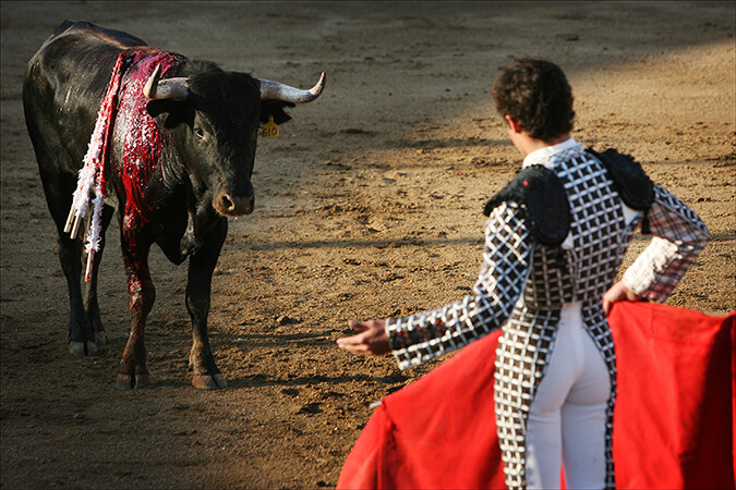 A bloodied bull prepares to charge matador Emanuel Lopez at La Paloma bullring in Puerto Vallarta, Mexico
