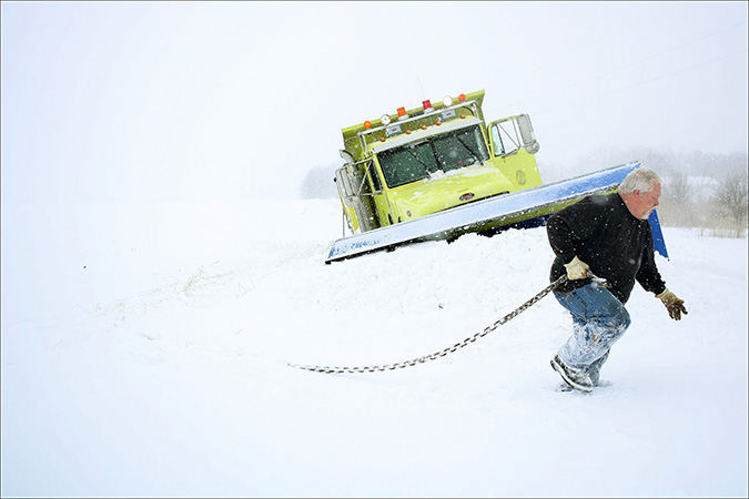 Lake County Highway Department snow plow driver Roger Ohlenkamp prepares his chain to tow his truck out of a ditch in Crown Point, Wednesday, Feb 2, 2011. The truck ended up in a ditch due to a civilian driver that would not move.
