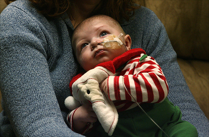 Young Seth Petreikis is held by his mother Becky Petreikis as she explains the outpour of sympathy and the news that Seth will receive the thymus transplant that was not covered by their Medicaid provider, Friday, Dec  10, 2010.