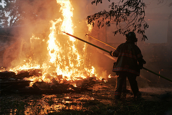 Firefighters Jon Klein and Ed Roy use pike poles to tear down a burning home at 3315 Ridge Road in Highland, Tuesday, July 27, 2010. The house, which was purchased by the town of Highland, was intentionally set on fire for training purposes.  (Tim Hunt for the Post-Tribune)