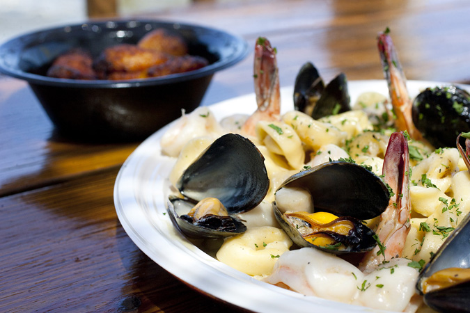 Seafood cheese tortellini with mussells, scallops and shrimp with garlic sauce. served with plantains